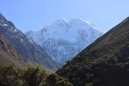 Snow-capped mountain peak surrounded by green valleys under a clear blue sky