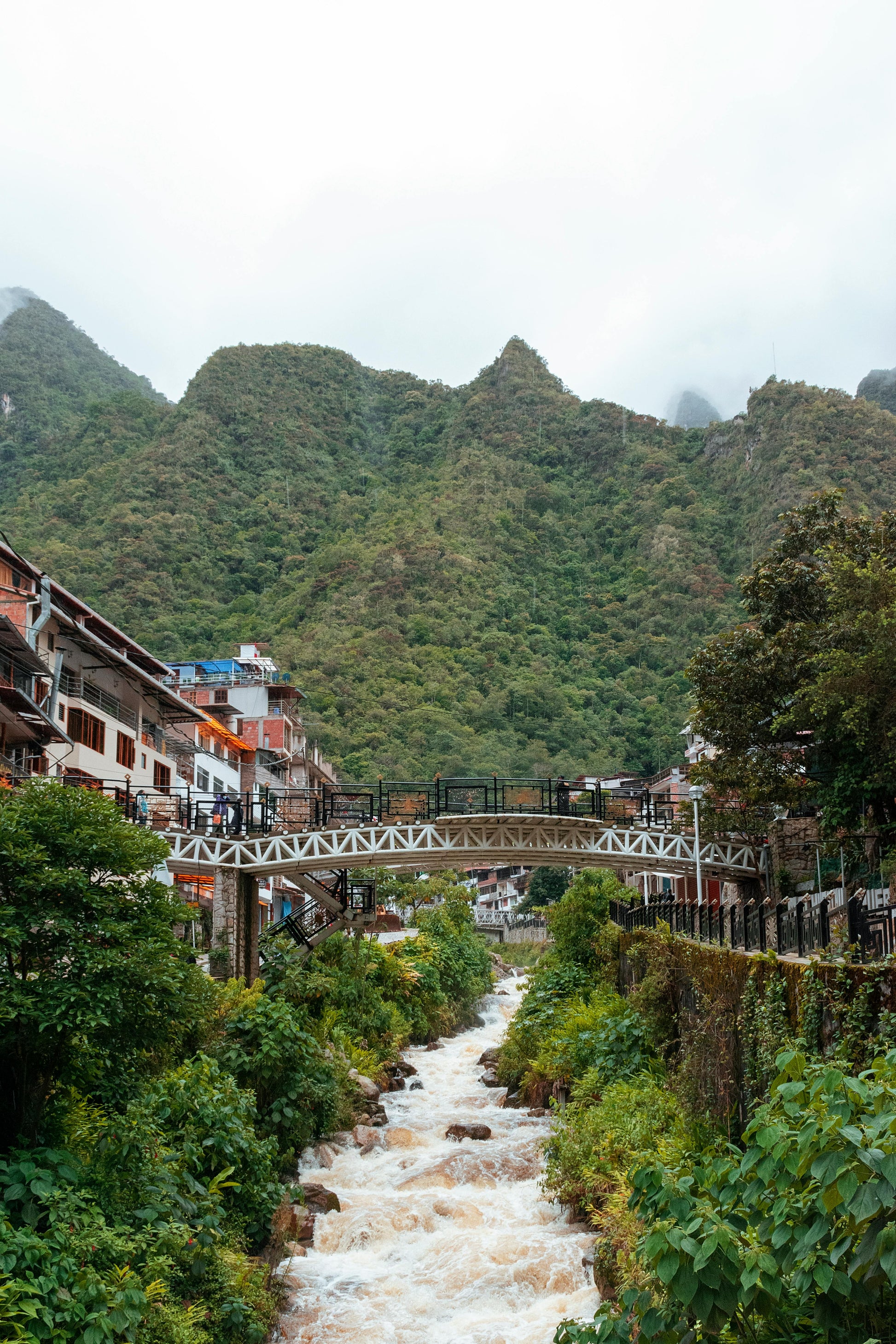 Scenic view of a mountainous area with a river and buildings.